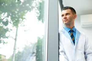 A doctor looking out a window contemplating their success.