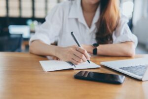 A woman sitting with a laptop and notepad working on determining goals