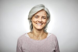 A woman in her 60s smiles showing off her pretty teeth.