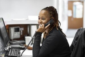 A front desk person answering the phone with a welcoming attitude