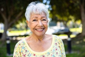 A smiling older woman in a yellow floral shirt