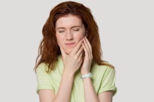 A young red-head holding their jaw from wisdom teeth pain