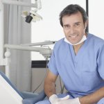 A smiling dentistsitting in an operatory